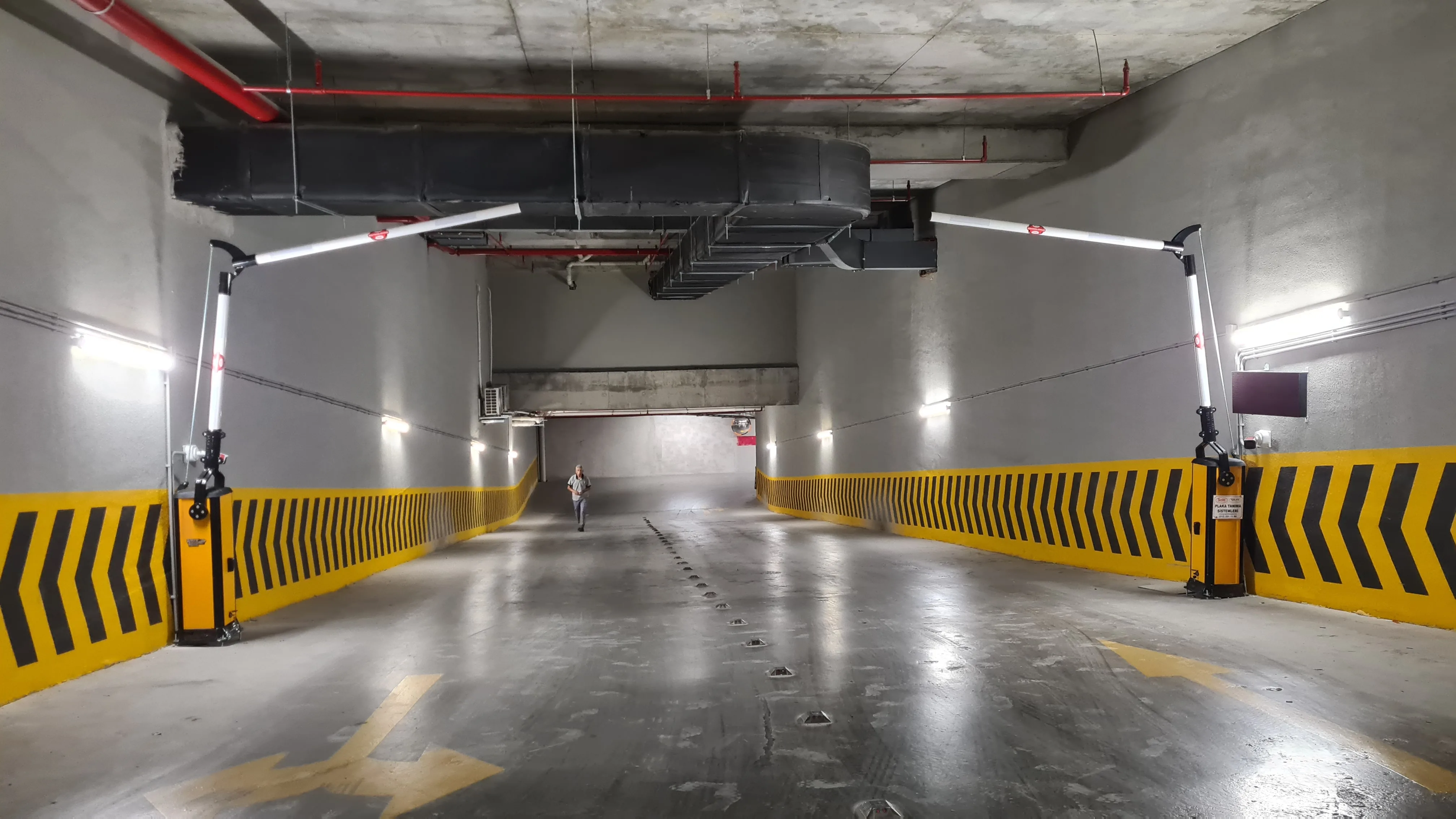 Geniş kapalı otopark rampasında karşılıklı iki kollu bariyer