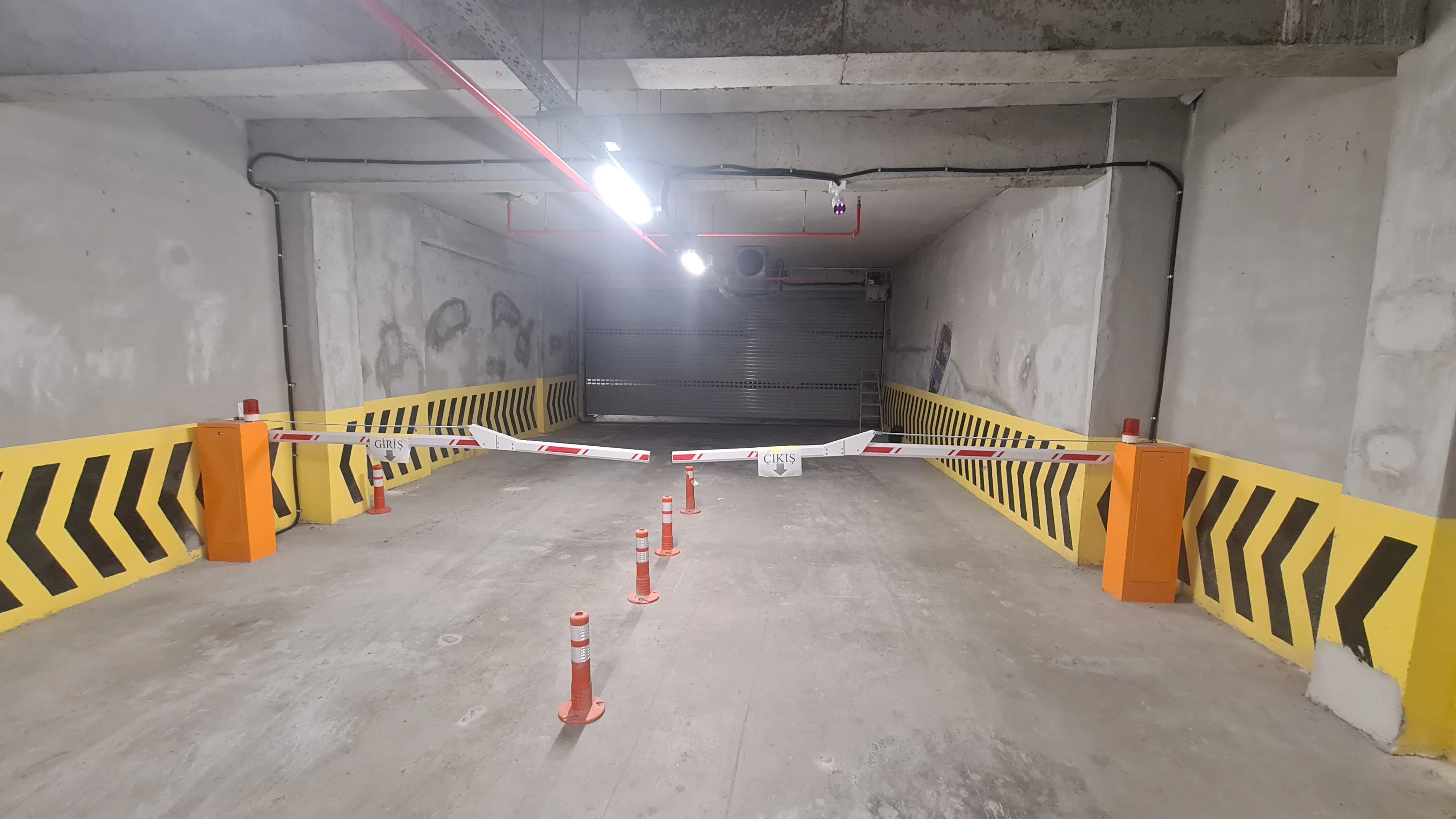 Kapalı otopark girişinde GİRİŞ-ÇIKIŞ çift kollu bariyer ve loop sensör alanı